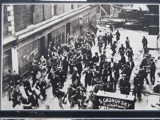 壁画前の掲示板にある1936年の「ケーブル・ストリートの戦い」時の写真