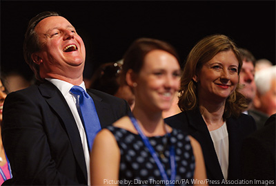 9月30日、オズボーン財務相の演説を聞きながら、同財務相夫人（写真右）の横で笑い声を上げるキャメロン首相（同左）